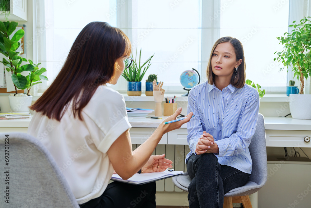 Young woman at mental therapy, talking to female psychologist - obrazy, fototapety, plakaty 