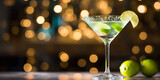 Cold gin gimlet cocktail decorated with lime on table, blurred light background 