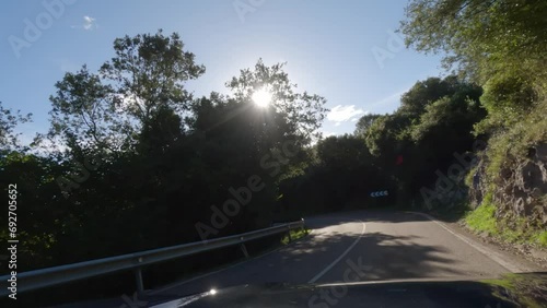 First person view, FPV, from dashcam of car driving mountain road down from Pena Cabarga outside Santander in Cantabria, Northern Spain, Europe. Road trip video in POV, with sunny bright blue sky photo