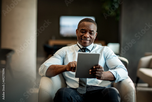 Smiling happy businessman using tablet in hotel lobby photo
