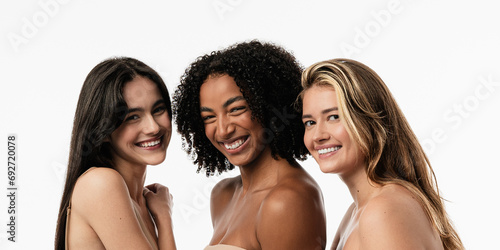 Female models of different ages celebrating their natural bodies in a studio. Three confident and happy women smiling cheerfully. Women standing together against a studio background.