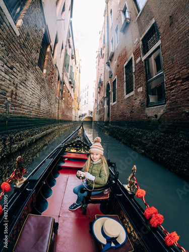 A young girl relaxes on a gondola, her gaze captivated by the sunset over the waters of Venice's Grand Canal photo