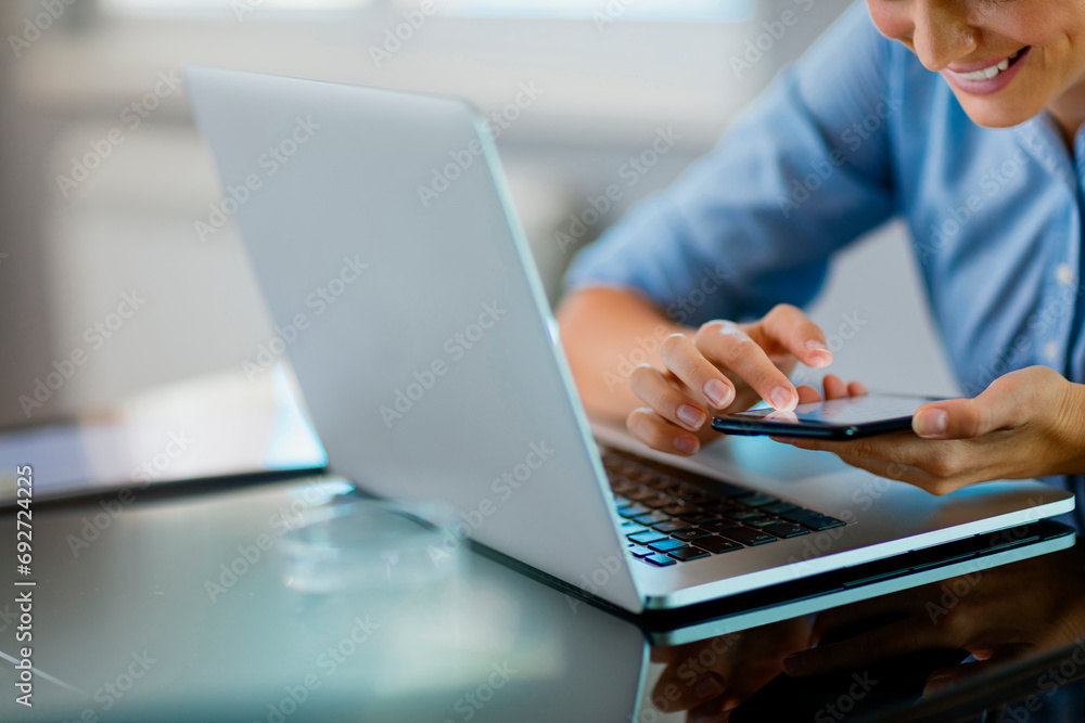 Woman using the smartphone at the laptop Woman using the smartphone at the laptop
