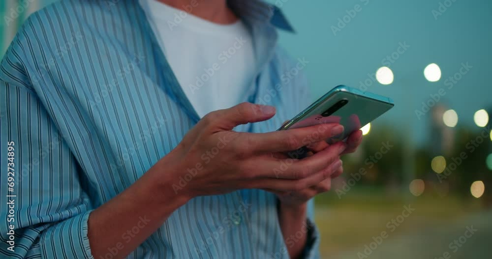 Female hand scrolling browsing on a smartphone at night time. Close-up of person using smartphone, browsing social network Female hand scrolling browsing on a smartphone at night time. Close-up of person using smartphone, browsing social network