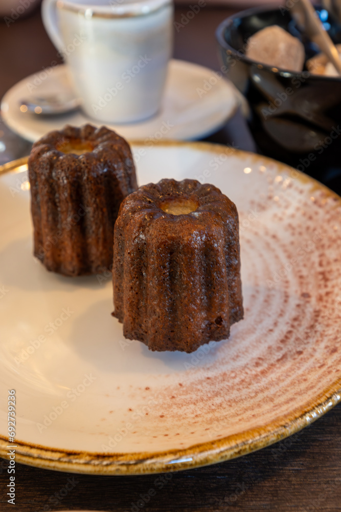 Canele, French pastry flavored with rum and vanilla, specialty of Bordeaux region, France, served with cup of black coffie in French restaurant Canele, French pastry flavored with rum and vanilla, specialty of Bordeaux region, France, served with cup of black coffie in French restaurant
