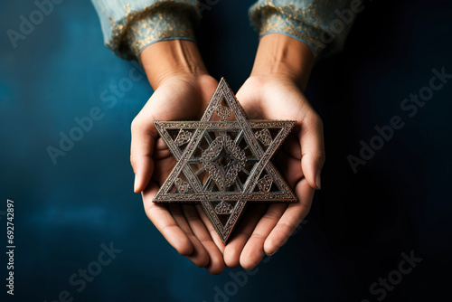 A woman holding an old and rusty star of David in their hands on blue abckground.