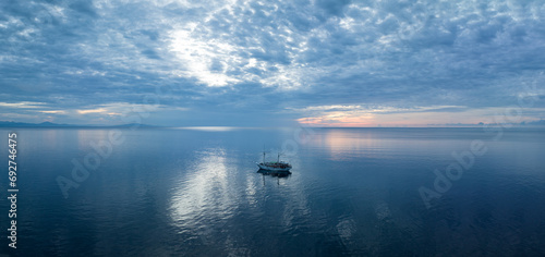 A phinisi schooner, used as a diving live aboard, drifts in calm seas at sunrise near Ambon, Indonesia. This beautiful area harbors extraordinary marine biodiversity. photo