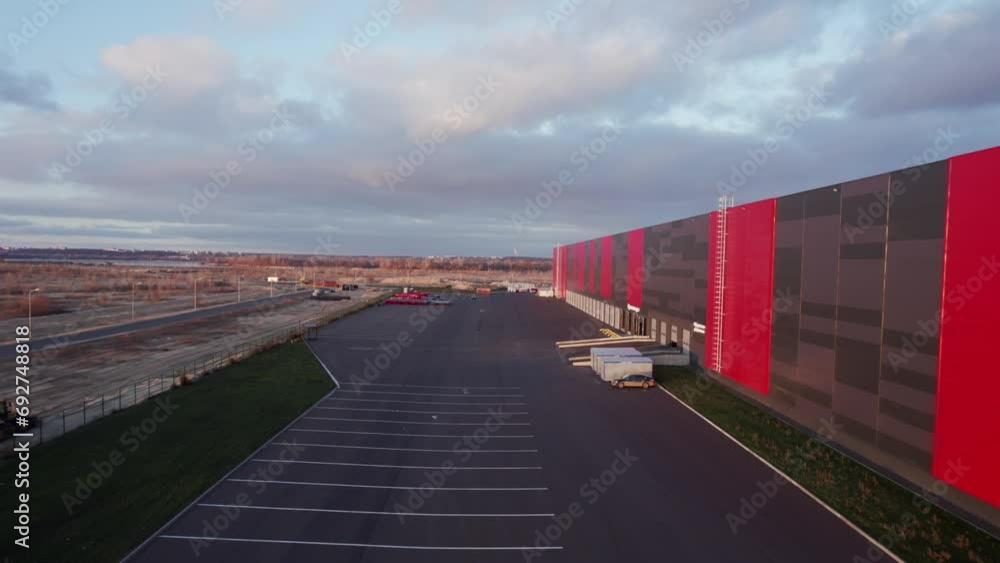 Storage area with cars on parking space in winter season. Large warehouse area can accommodate number of trucks for loading goods at sunset Storage area with cars on parking space in winter season. Large warehouse area can accommodate number of trucks for loading goods at sunset