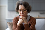 Unhappy depressed senior woman suffering from depression and loneliness, thinking about problems, sitting on couch at home
