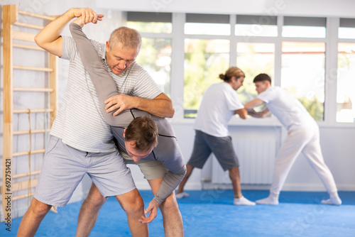 Concentrated men in sport club during self-defense training, sparring and practicing technique of hand grab