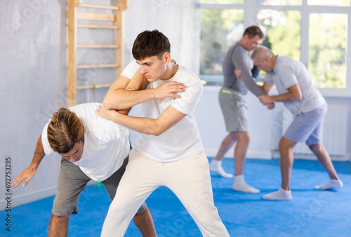 Two athlete men in sportswear practicing self-defense sparring in the hall
