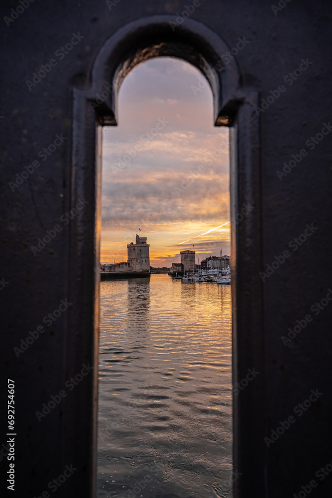view through balustrade of the old harbor of La Rochelle at blue hour with its famous old towers.