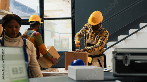 Depot workers team packing boxes with supplies, preparing stock for shipment order. Warehouse employees putting merchandise or goods in cardboard packages, products on racks and shelves. photo