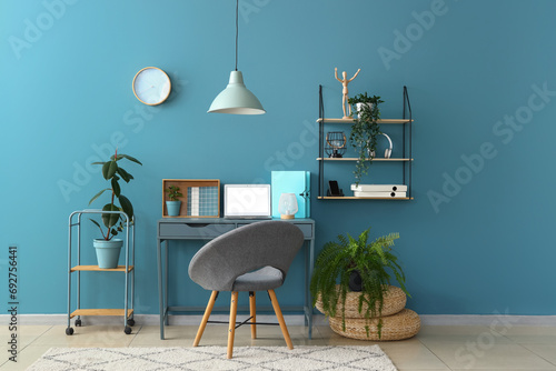 Stylish interior of room with comfortable workplace and houseplants photo