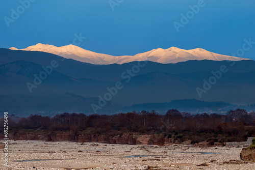 A river in Thessaly and the snowy peaks of Olympus mountain in Greece. Blue sky in winter time.