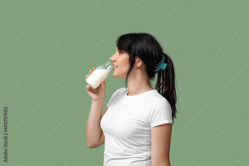 Pretty young woman drinking milk on green background Pretty young woman drinking milk on green background