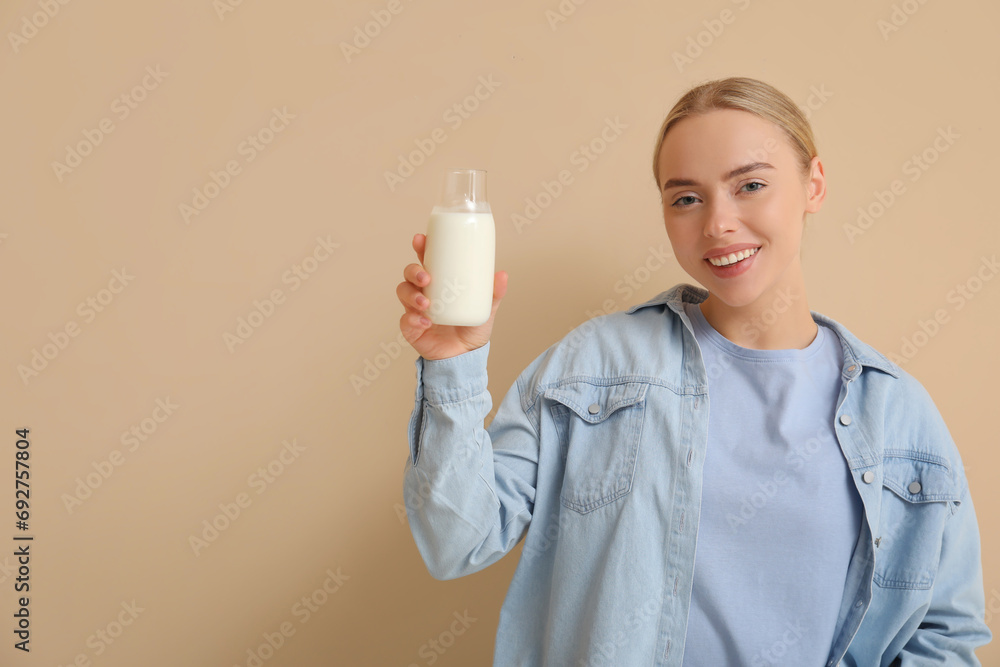 Pretty young woman with glass bottle of milk on beige background Pretty young woman with glass bottle of milk on beige background