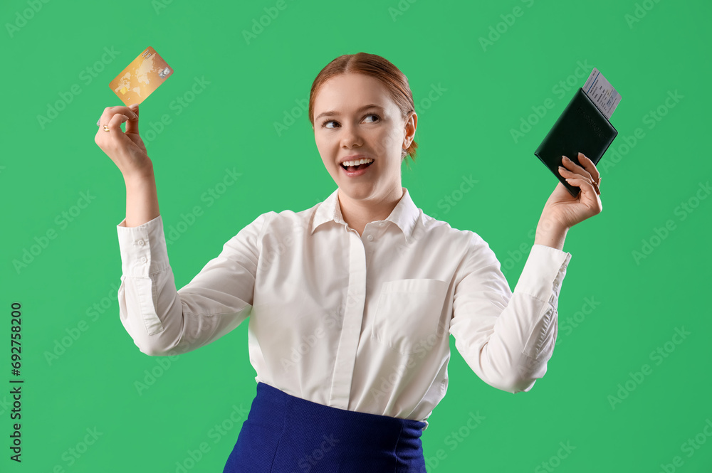 Young businesswoman with credit card and passport on green background