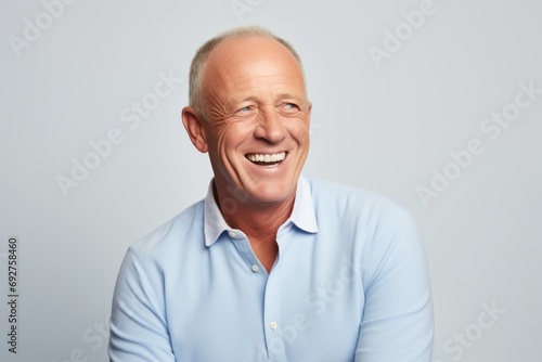 Portrait of a happy senior man laughing and looking at camera against grey background
