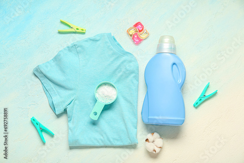 Different laundry detergents with clean t-shirt and clothespins on light blue background