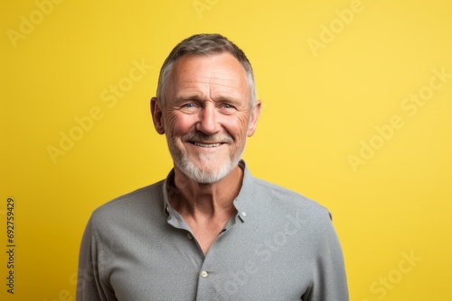 Portrait of a happy senior man smiling at the camera on yellow background