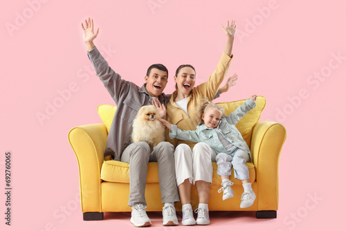 Happy family sitting on sofa against pink background