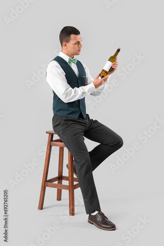 Young barman with bottle of...