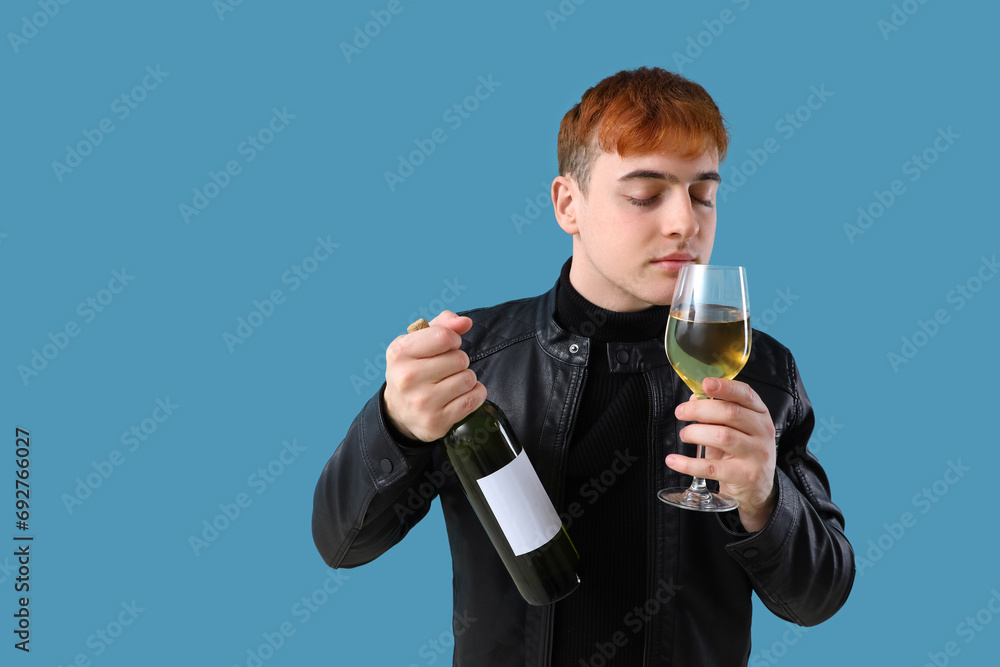 Young man with bottle and glass of wine on blue background Young man with bottle and glass of wine on blue background