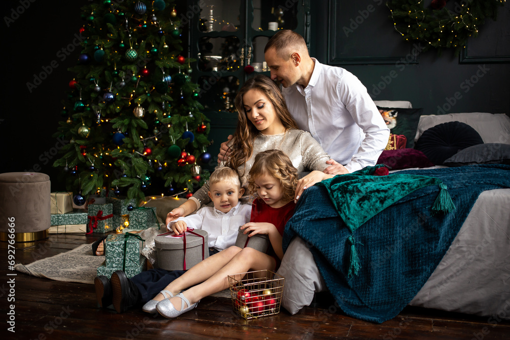 Happy young mother, father and two children playing home on Christmas holidays.