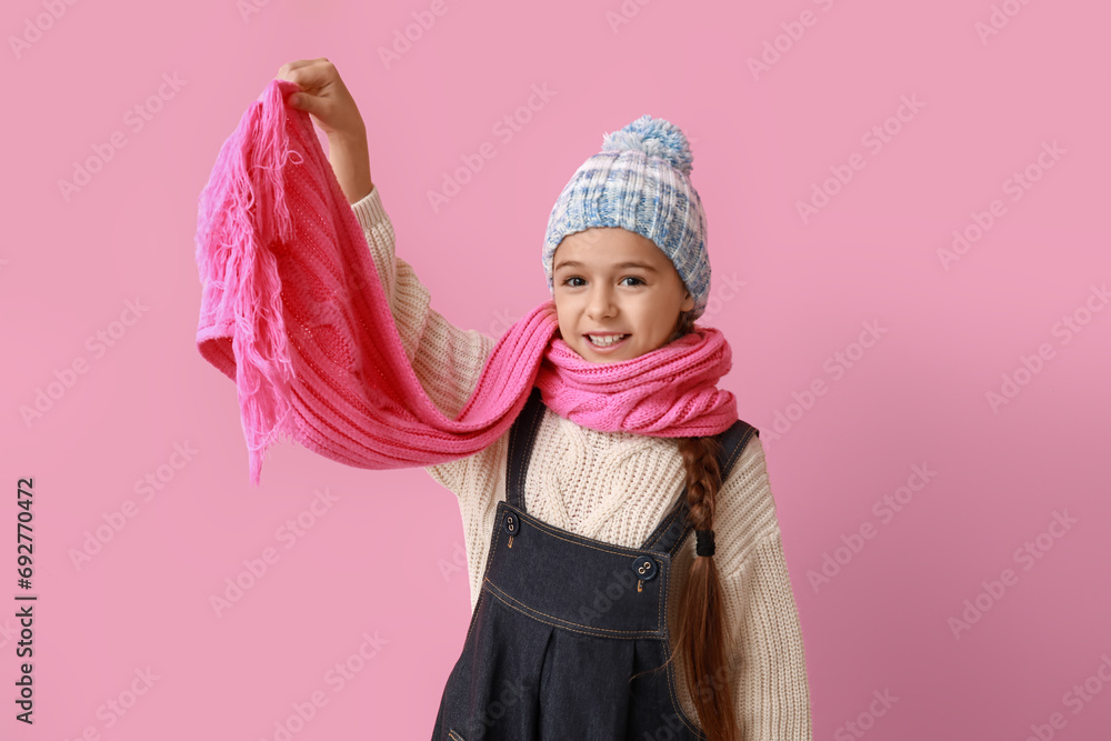 Cute little girl in warm hat and scarf on blue background