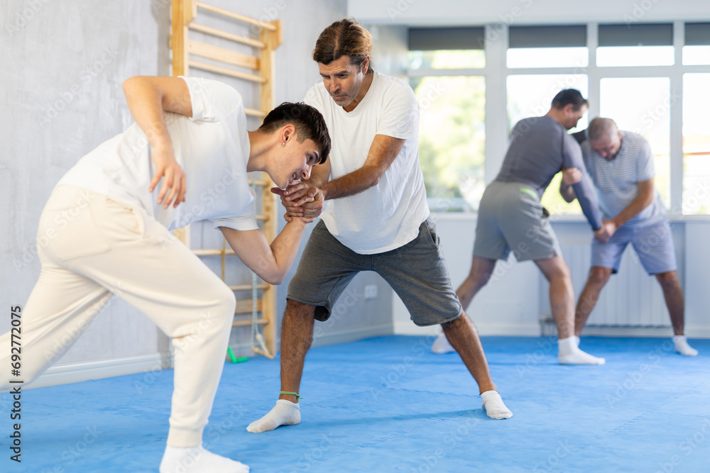Obraz premium Adult man and young guy training judo techniques in studio..