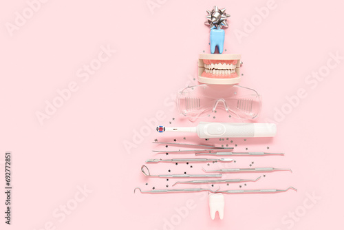 Christmas tree made of dentist's tools on pink background photo