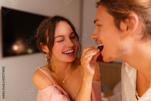 Happy, couple in love eating, woman feeding her boyfriend, romantic date in restaurant