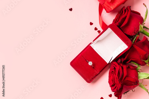 Beautiful composition with engagement ring and rose flowers on pink background. Valentine's day celebration photo