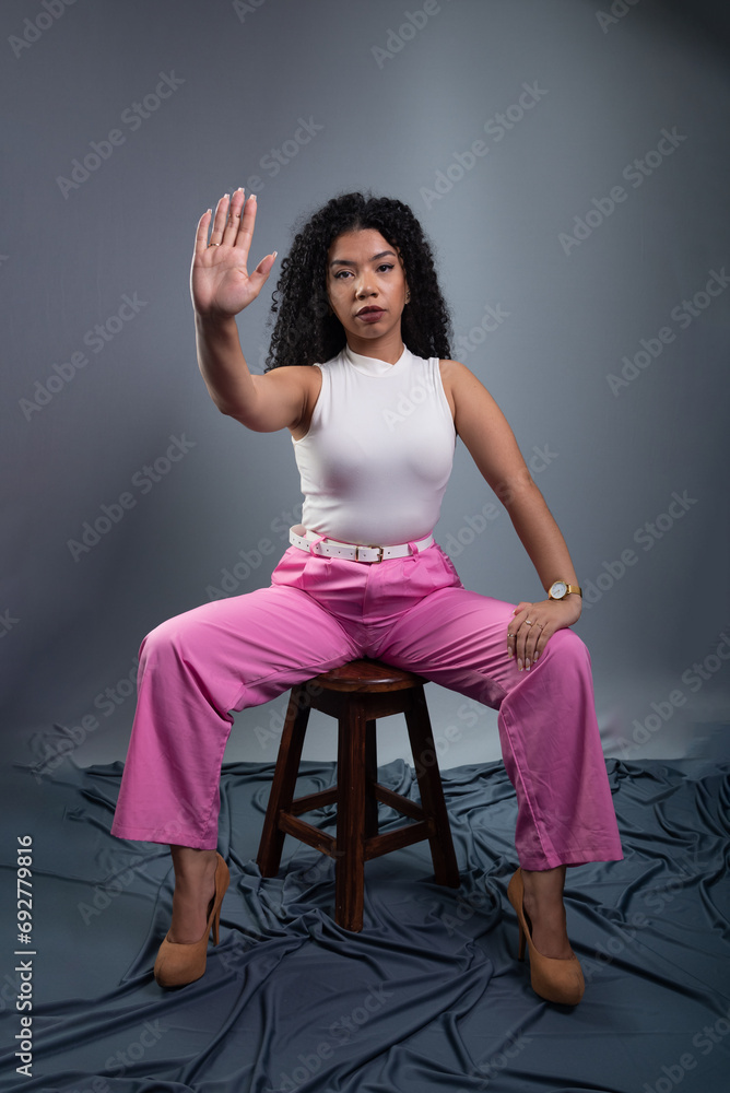 Beautiful woman sitting, making a stop sign with her right hand Beautiful woman sitting, making a stop sign with her right hand
