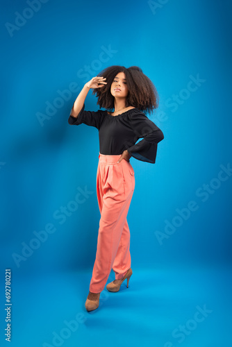 Beautiful young woman, standing, in casual clothes, touching her black power hair.