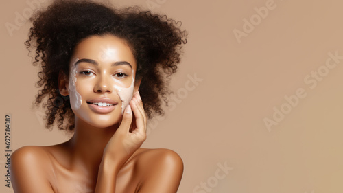 Afro woman with a healthy glowing skin is applying a skincare product. photo