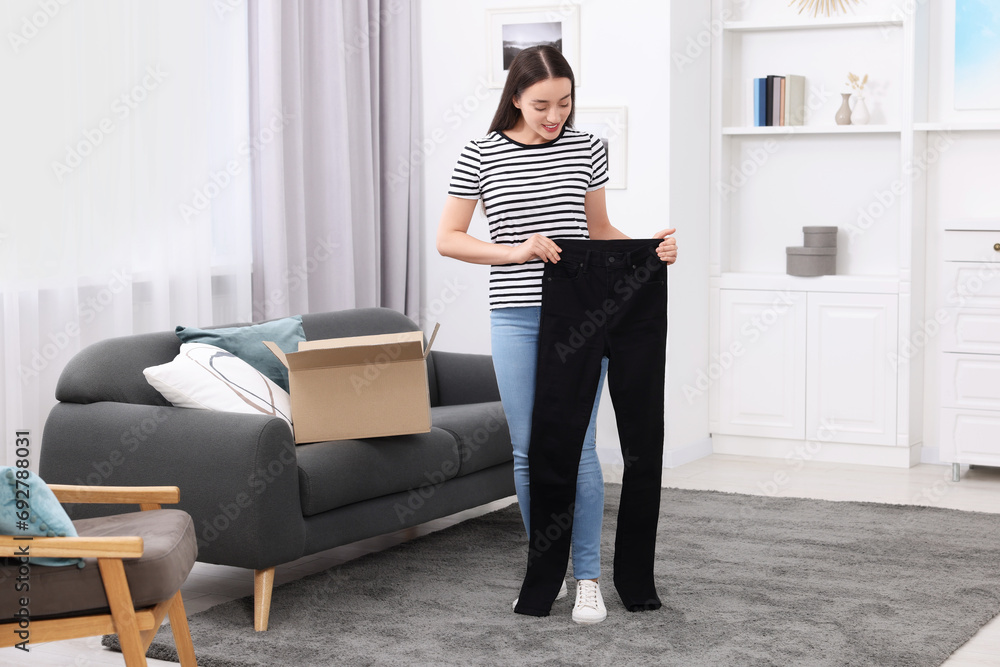 Happy woman with stylish black jeans at home. Online shopping