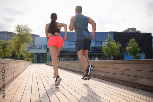 Healthy lifestyle. Couple running outdoors on sunny day, low angle view