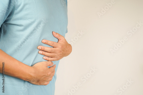 male having stomach ache, bending over and holding hands on stomach, uncomfortable due to stomach cramps, gastric pain