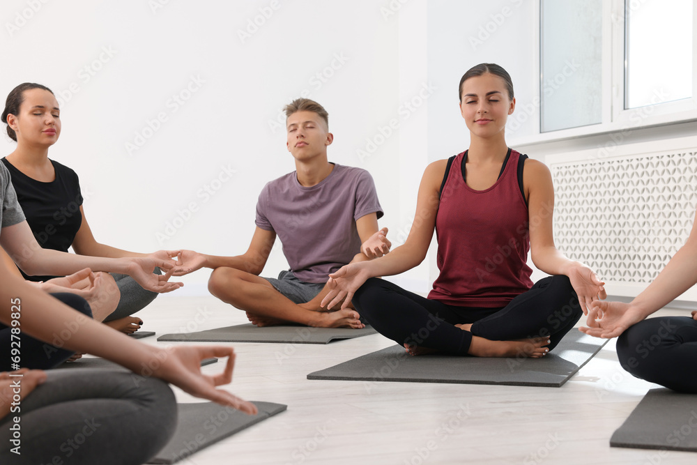 Group of people practicing yoga on mats indoors Group of people practicing yoga on mats indoors