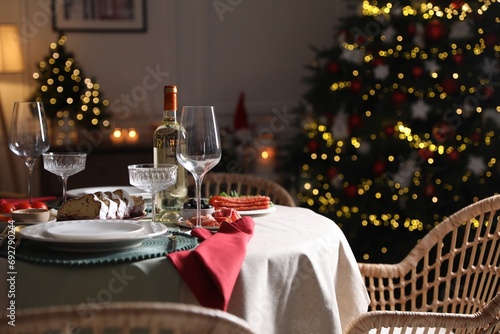 Christmas table setting with bottle of wine  appetizers and dishware indoors