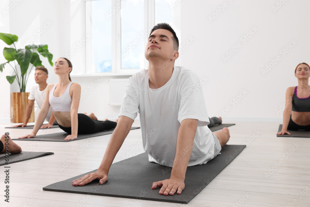 Obraz premium Young man practicing yoga during group lesson indoors