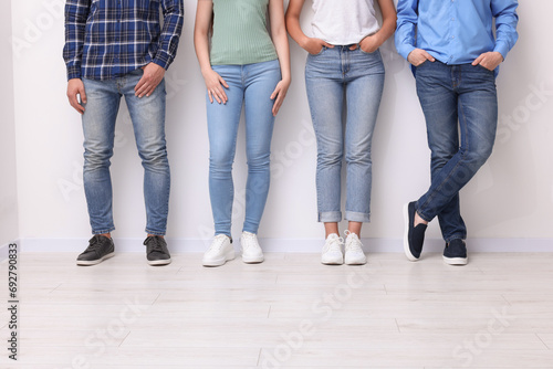 Group of people in stylish jeans near white wall indoors, closeup