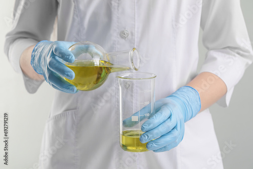 Scientist developing cosmetic oil on white background, closeup