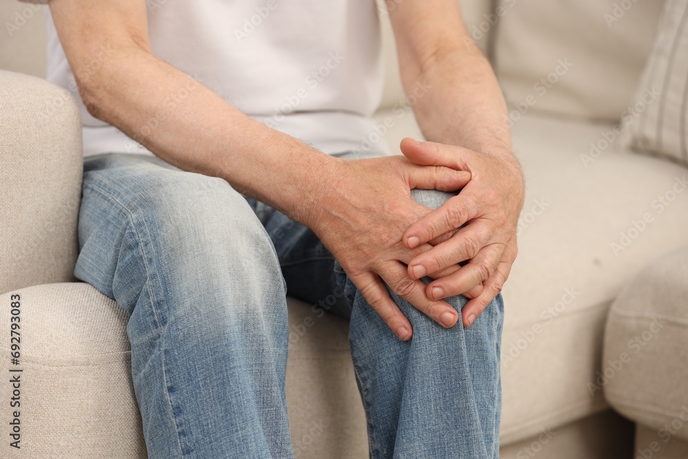Senior man suffering from knee pain on sofa, closeup. Rheumatism symptom Senior man suffering from knee pain on sofa, closeup. Rheumatism symptom