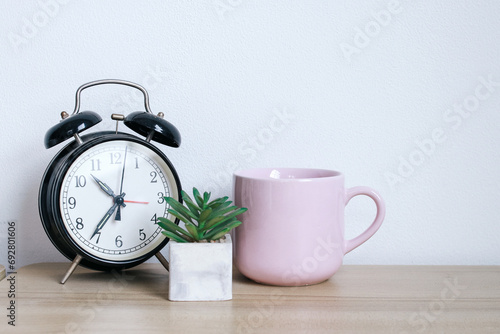 Alarm clock, succulents and a mug on wooden table, minimal stylish working desk photo