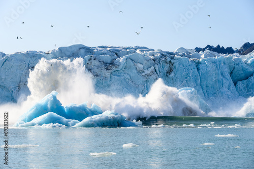 Dramatic ice calving from the Monacobreen Glacier in Liefde Fjord, small tidal wave and icebergs floating in the arctic ocean around Svalbard, signs of climate change and global warming 