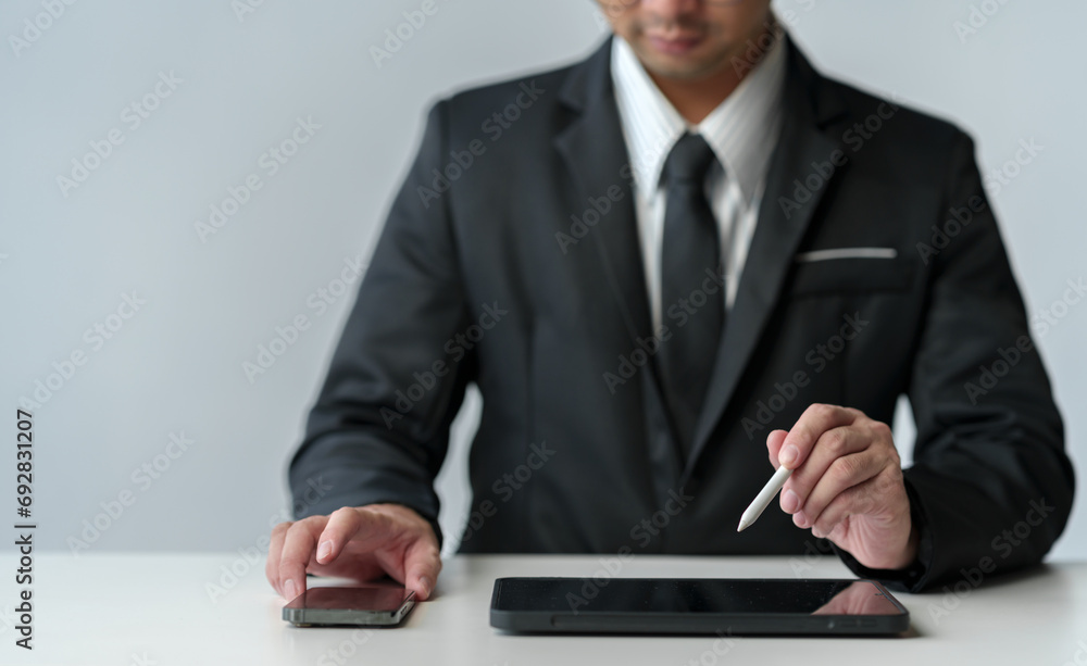 Businessman working on laptop computer and tablet on table at office. Working online. Using pen, index finger on digital tablet screen. Work mindset concept, lifestyle idea Businessman working on laptop computer and tablet on table at office. Working online. Using pen, index finger on digital tablet screen. Work mindset concept, lifestyle idea