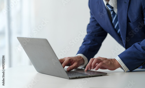 businessman working on laptop computer Print email check work Submit information online on white desk for successful business goals in office.